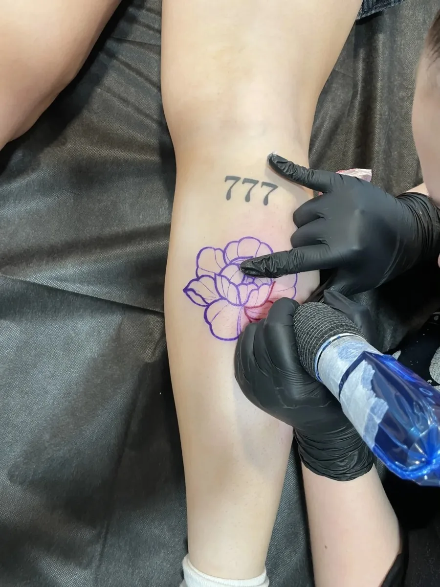 Artist working on a peony tattoo stencil